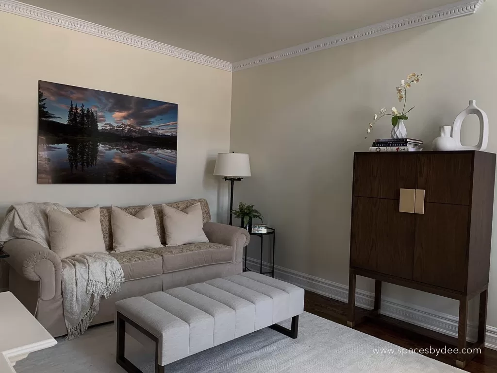 vintage and modern sitting/living room. The room uses vintage furniture. A vintage sofa, and modern rug, an ottoman and a wine cabinet.